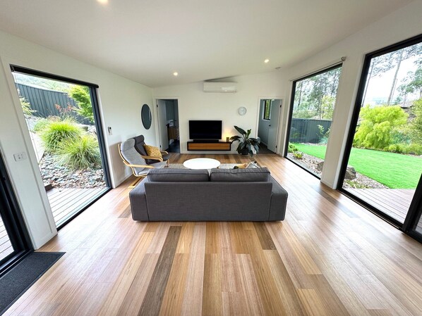 A modern living room with a grey sofa, a round coffee table, and a TV.