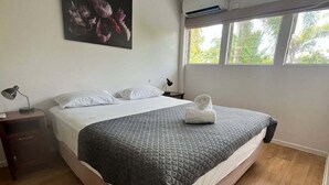 A neatly made bed with a quilted blanket, a pillow, and a rolled towel on the side. - Standard Three-Bedroom Villa with Private Pool (Palm Cove)