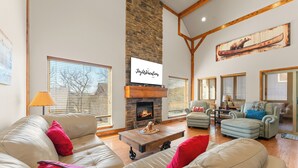 A spacious living room with a fireplace, leather sofas, and a large window. - Pools Pvt Hot Tub near Thunder Ridge & Big Cedar (Hollister)