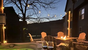 An outdoor hot tub area with wooden chairs and tables, surrounded by string lights. - Pools Pvt Hot Tub near Thunder Ridge & Big Cedar (Hollister)