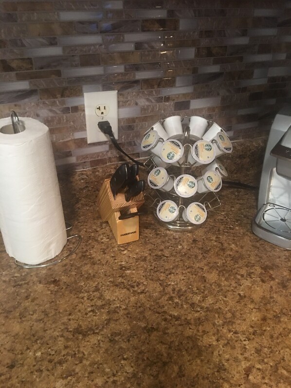 A kitchen with a granite countertop, a coffee machine, a Farberware coffee grinder, and a paper towel holder.