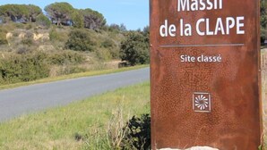A sign for "Massif de la CLAPE" with a textured surface and a logo.