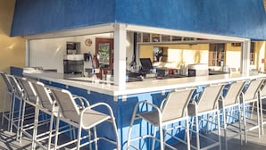 Een bar met een toog, barstoelen en een zithoek met tafels en stoelen.