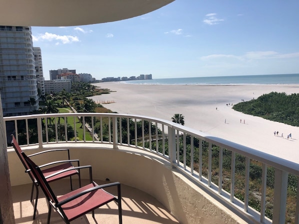 Un balcon donnant sur une plage, avec quelques chaises et une rambarde.