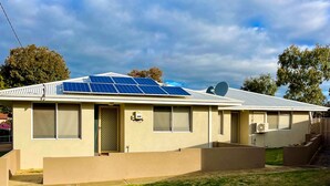 Un edificio de una sola planta con techo plano, paneles solares y una antena parabólica.