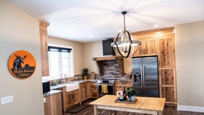 Una cocina moderna con armarios de madera, estufa integrada y un refrigerador de acero inoxidable.