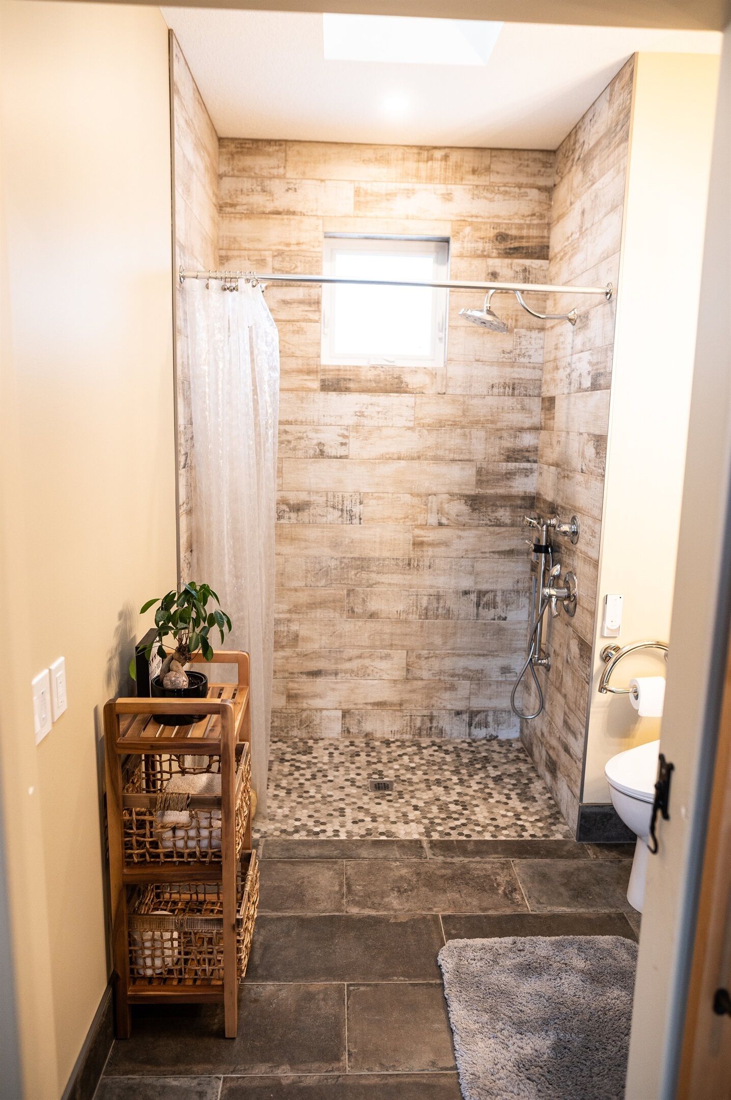 A shower with a wooden wall, a small window, and a tiled floor.
