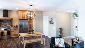 Una cocina moderna con armarios de madera, un refrigerador de acero inoxidable y una mesa de comedor de madera.