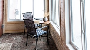 Interior de madera con un farol colgante, una pared con ventanas y una mesa con sillas.