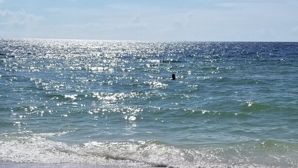 Una playa con cielo despejado y mar tranquilo.