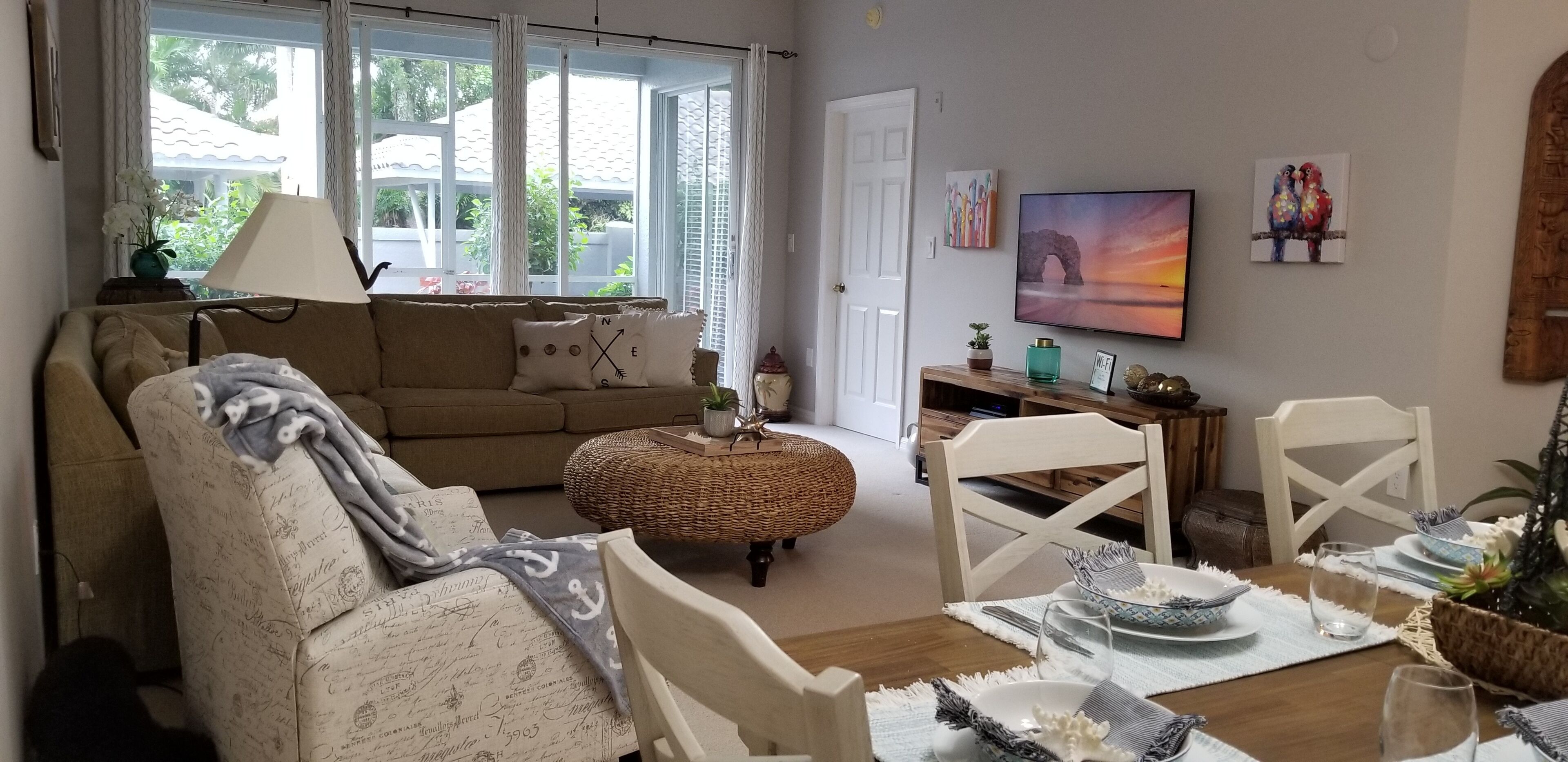 Ein gemütliches Wohnzimmer mit einer Couch, einem Esstisch für zwei Personen und einem Fernseher an der Wand.