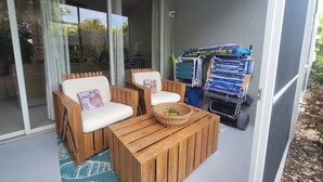 Un balcón con mobiliario de madera, una cesta de mimbre y una pila de toallas de colores.