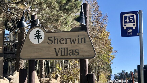 Un panneau en bois portant l’inscription « Sherwin Villas » et un symbole représentant un arbre.