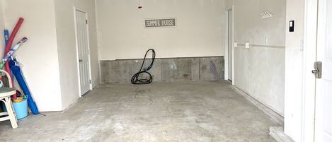 A clean, empty garage with a concrete floor, a ceiling fan, and a sign reading "SUMMER HOUSE".