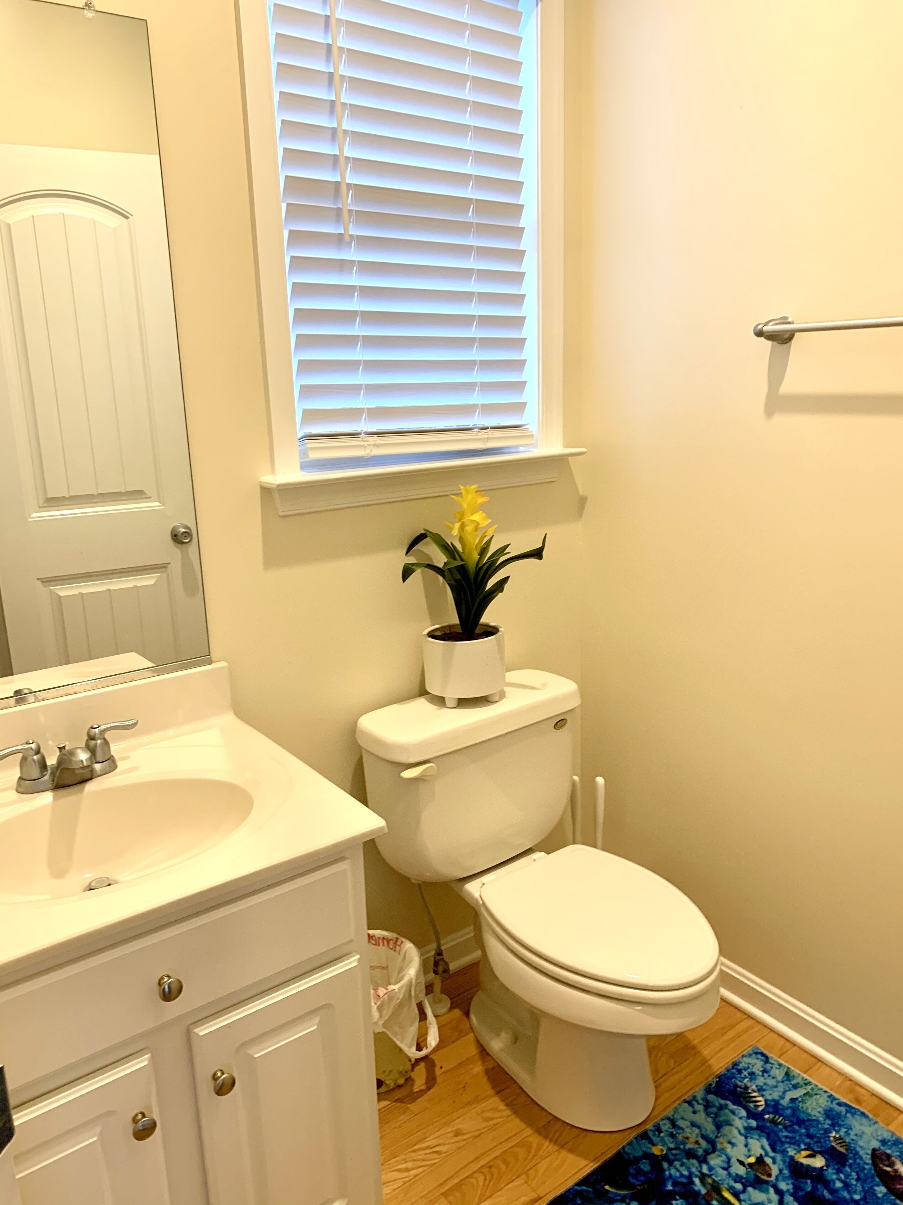 Een badkamer met een wit wastafelmeubel, toilet en raam met zonwering.