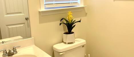 A bathroom with a white sink, toilet, and window with blinds.