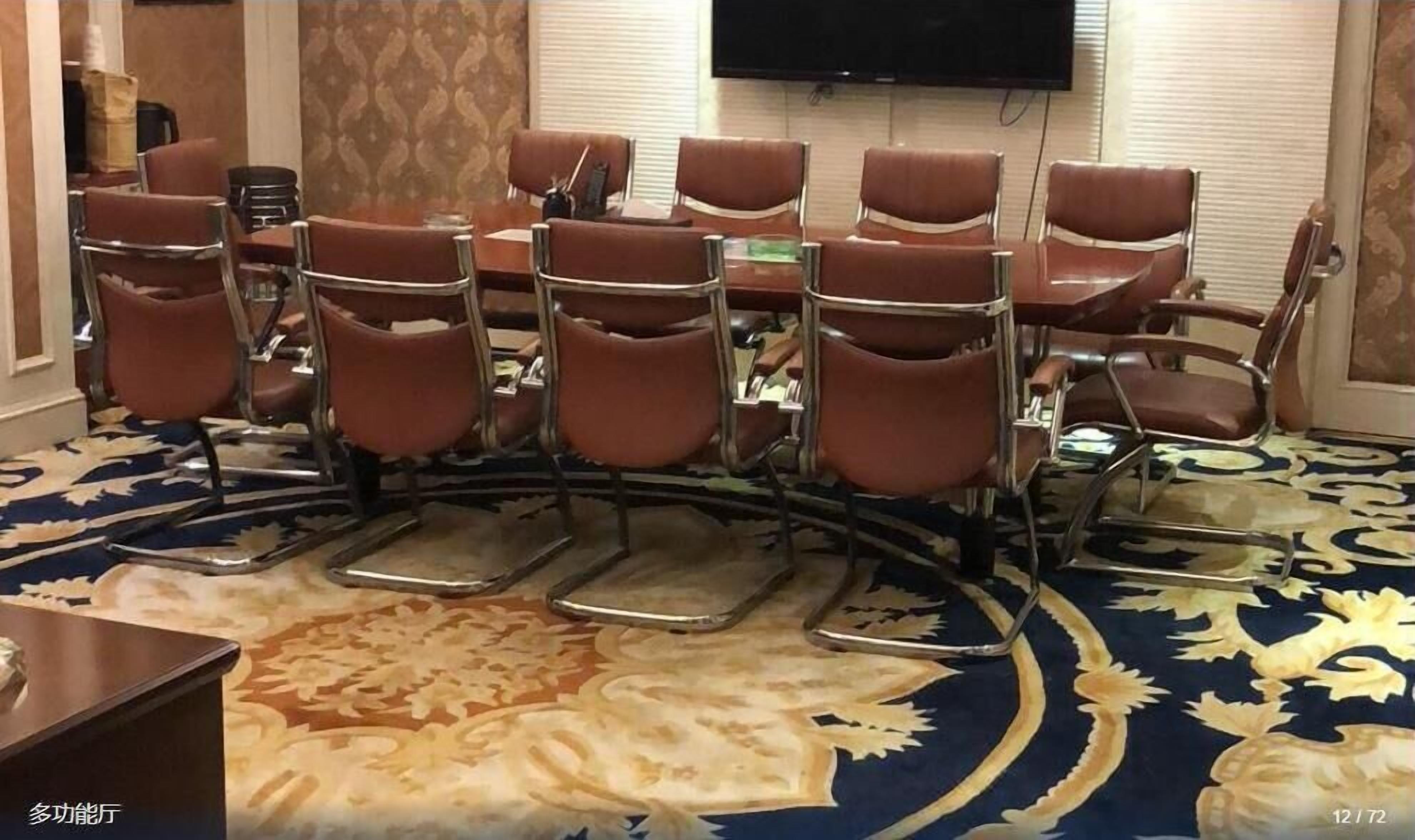 A conference room with a large table and multiple brown leather chairs.