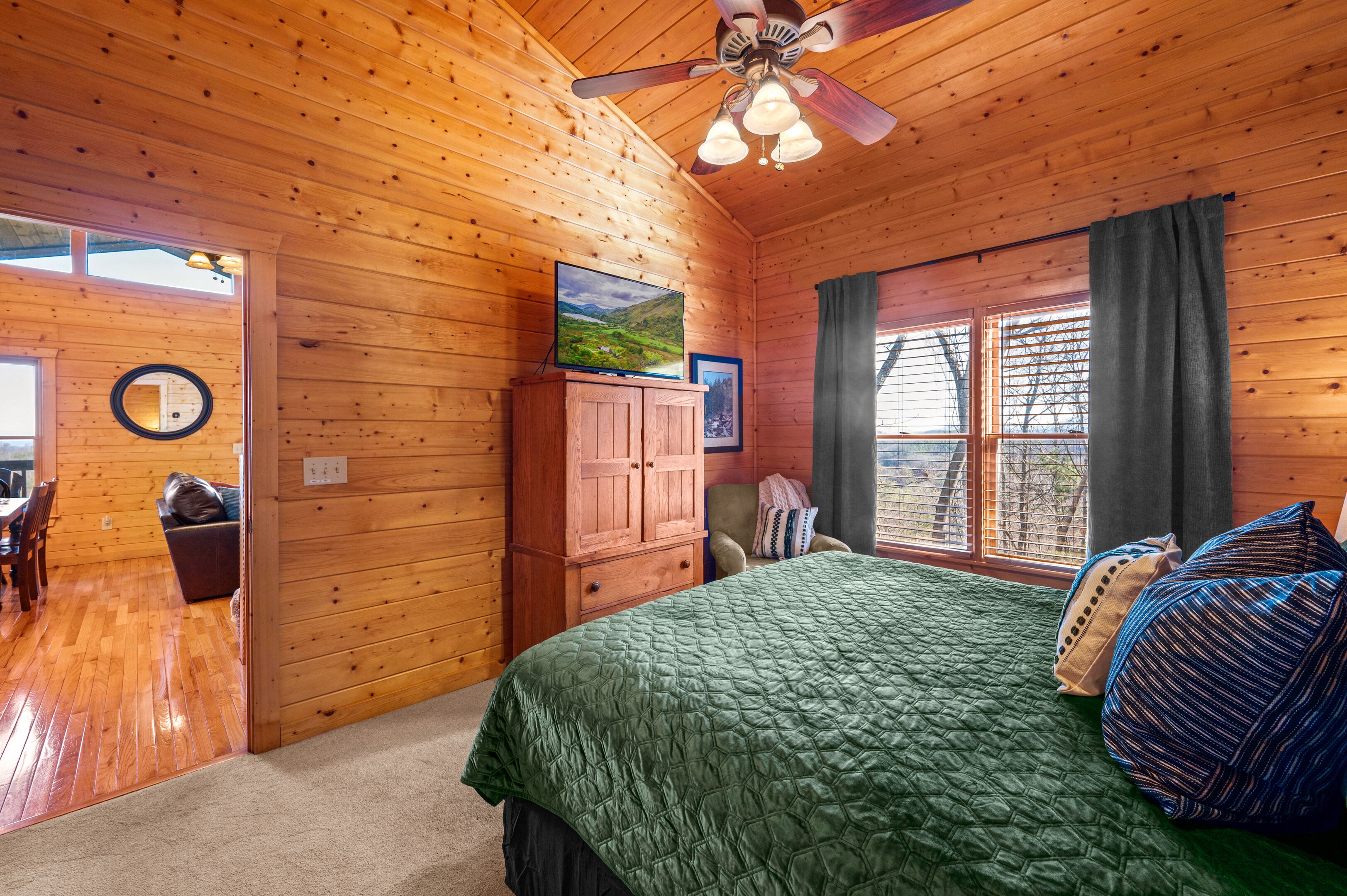 Dormitorio de cabaña de madera con cama, armario, silla y ventilador de techo.