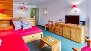 Una habitación moderna con una cama de madera, televisión, escritorio y silla.