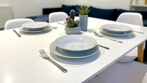 Mesa puesta con platos, cubiertos y una pequeña planta de cactus.