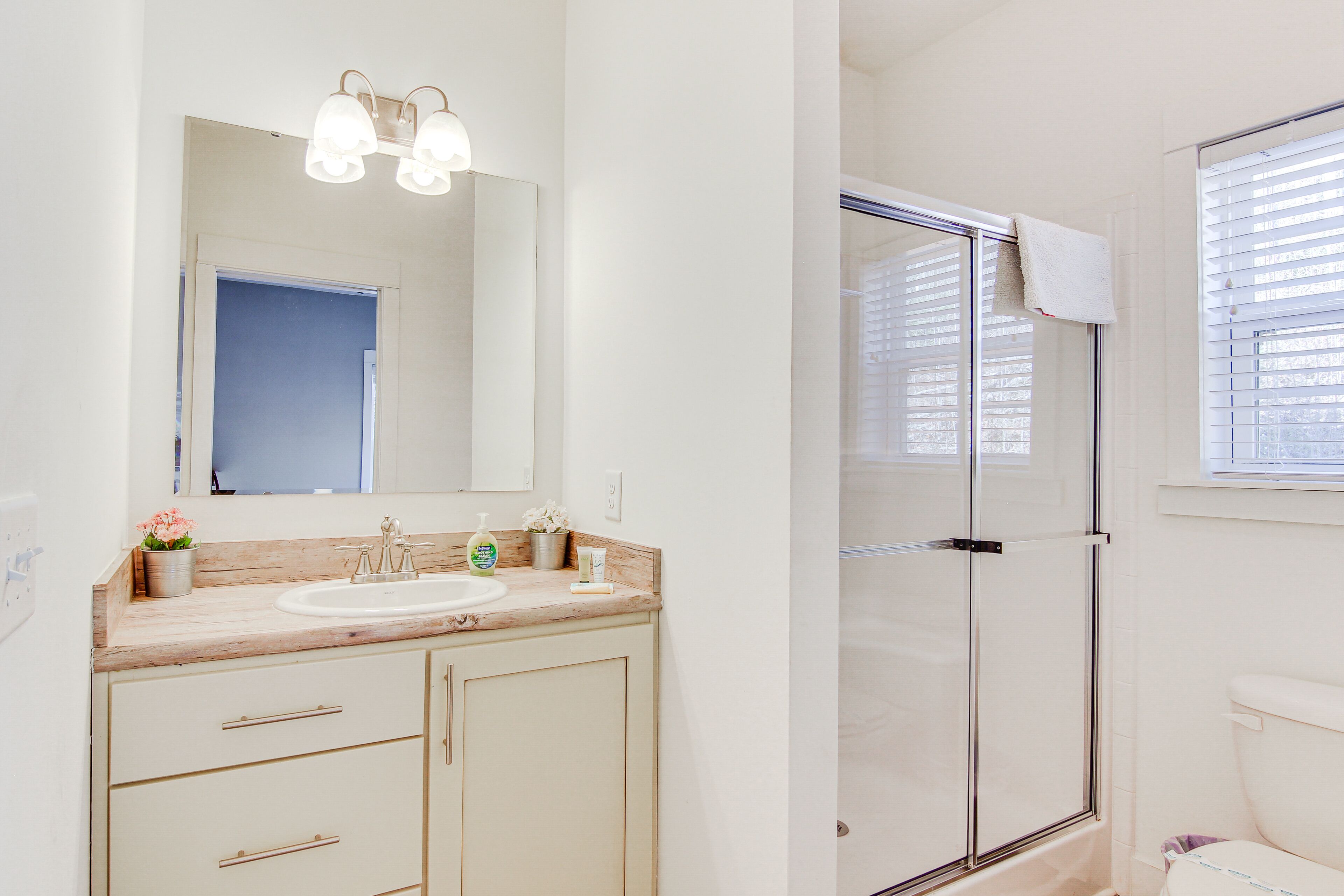 A bathroom with a wooden vanity, a sink, a mirror, and a glass-enclosed shower.