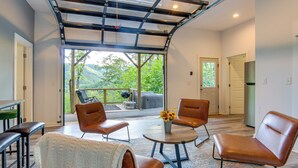Una sala de estar moderna con sillones de cuero, una mesa de centro y vistas a un balcón con mobiliario exterior.