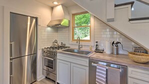 Una cocina moderna con electrodomésticos de acero inoxidable, encimera de madera y vistas al exterior a través de una ventana.