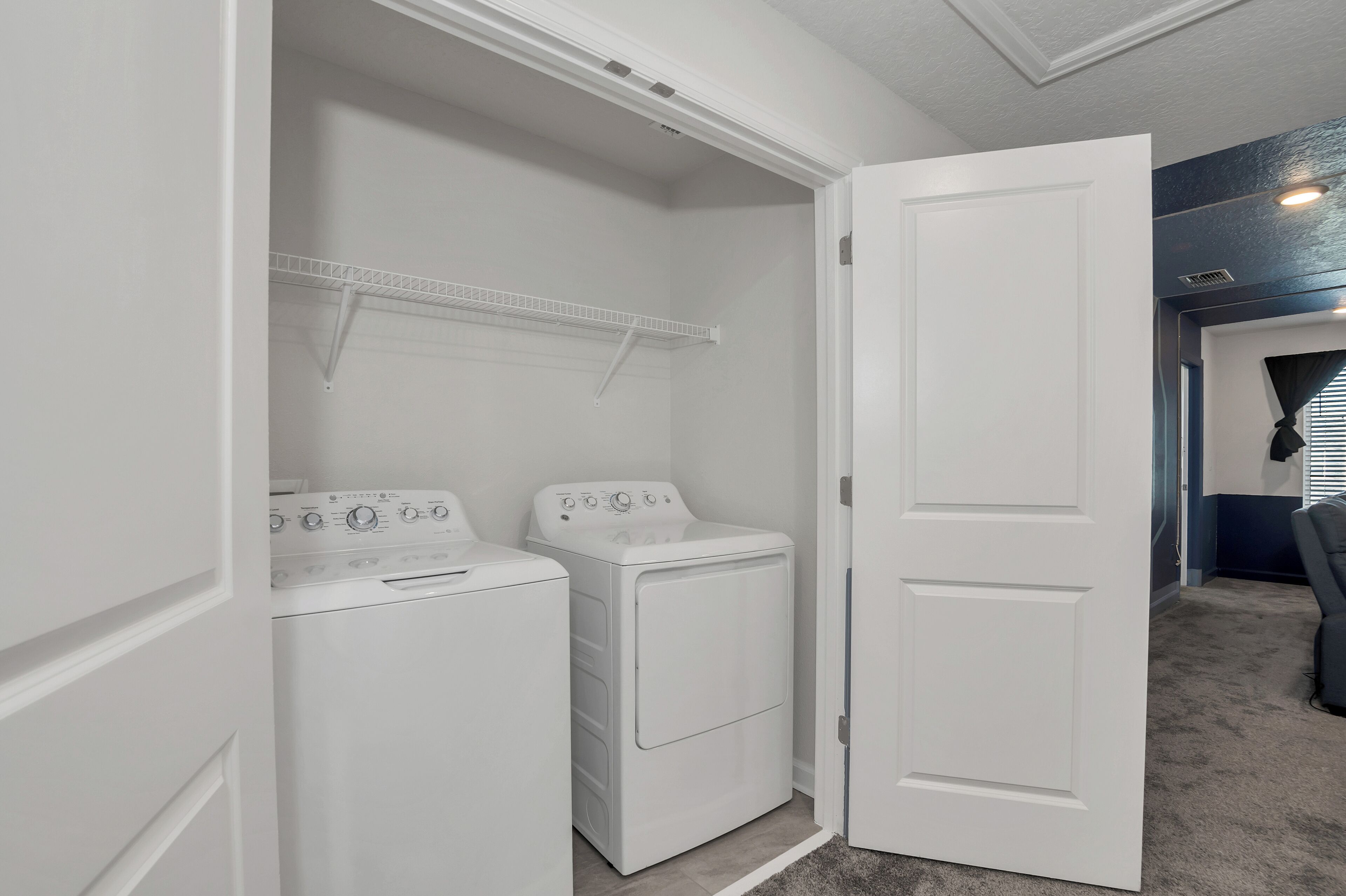 A laundry room with two white washing machines and a drying rack.