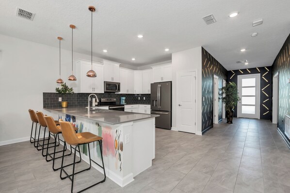 A modern kitchen with white cabinets, a central island, and bar stools.