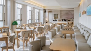 A modern dining area with tables and chairs, a bar, and a seating area with a sofa.