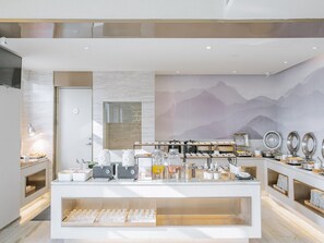 A modern kitchen with a buffet setup, including a coffee station and various food containers.