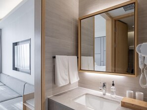 A modern bathroom with a large mirror, a sink with a faucet, a hairdryer, and a towel rack.