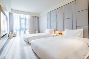A hotel room with two beds, a sitting area, and a large window.