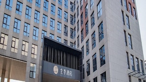A modern hotel building with a prominent entrance, multiple floors, and a clear sky.
