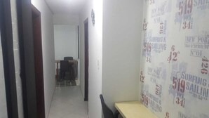 Un pasillo estrecho con una puerta a la izquierda y una pared con patrones de texto repetidos a la derecha.