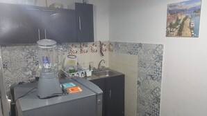 Una cocina con una licuadora, un lavamanos y un salpicadero de azulejos.