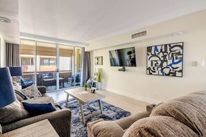 A modern living room with a sofa, a coffee table, and a TV mounted on the wall.