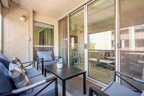 A balcony with a table, chairs, and a potted plant.