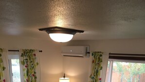 Ein gemütliches Wohnzimmer mit einem Holztisch, einem roten Sofa, einem grauen Sessel und einer Stehlampe.