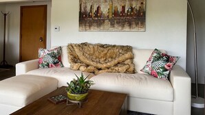 Ein Wohnzimmer mit einem weißen Sofa, einem Fellüberwurf und einem Stadtbild.
