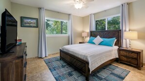 A bedroom with a bed, a ceiling fan, a nightstand with a lamp, a dresser, and a window with curtains. - Lakefront Escape / Fishing / Kayaks / Fast WiFi (Seguin)