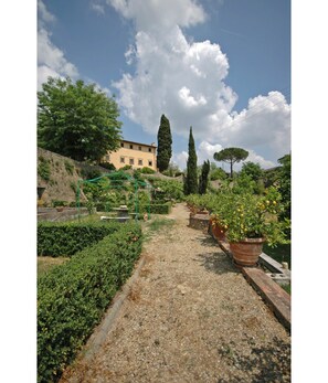 Stroll through the lush garden, leading to a traditional building with a stone facade.