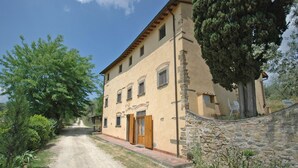 A two-story building with a stone wall and a gravel path leading to the entrance. - Le Vasche 4 - Apartment with pool (Romola)