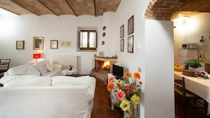 A cozy bedroom with a bed, a bedside table, a fireplace, and a dining area with a table and chairs. - Le Vasche 4 - Apartment with pool (Romola)