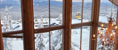 A cozy cabin with large windows offering a snowy mountain view.