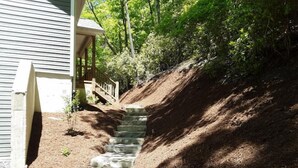 A staircase leading up to a house with a wooden deck and a small garden area. - BK's Hideaway, with fire-pit and bike storage (Pisgah Forest)
