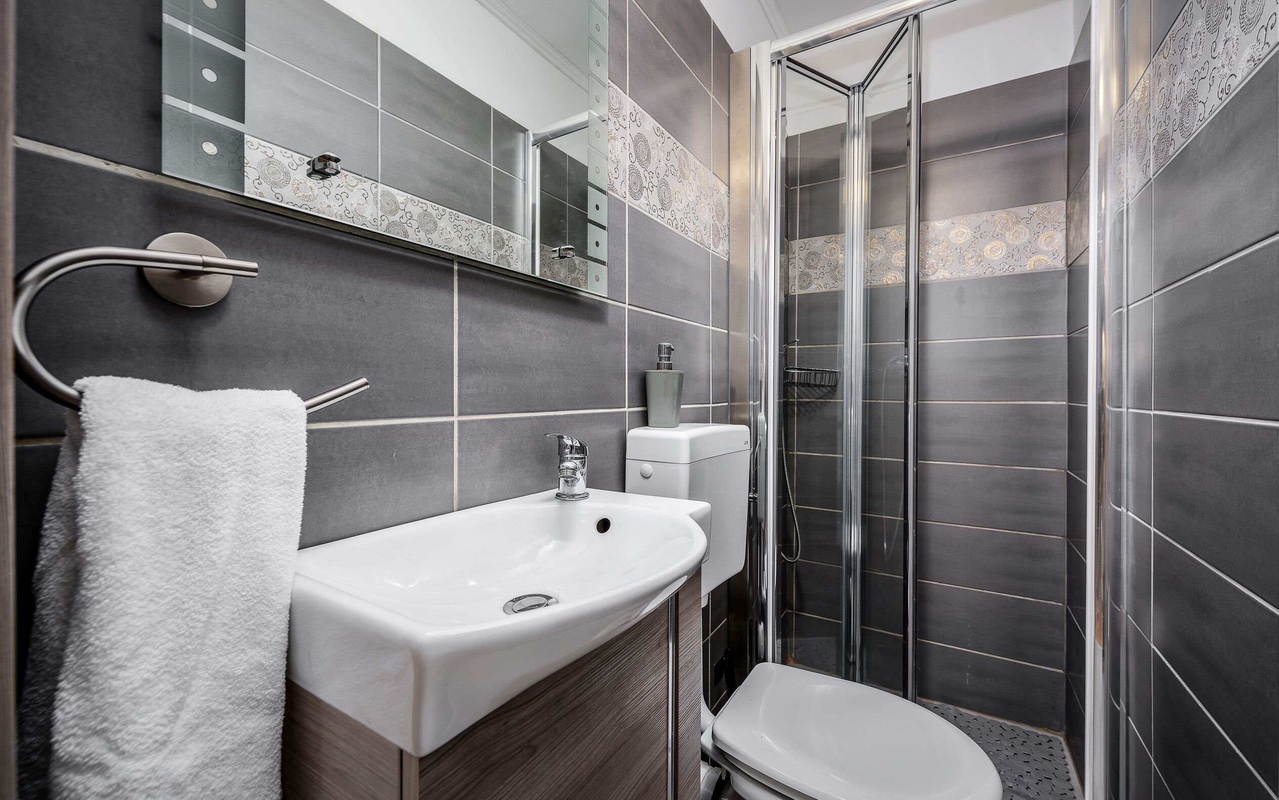 A modern bathroom with a white sink, toilet, and shower.