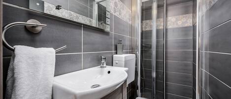 A modern bathroom with a white sink, toilet, and shower.