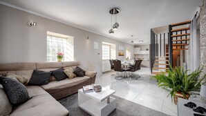 Uma sala de estar moderna com sofá, mesa de centro e um espaço de jantar com cadeiras e mesa.