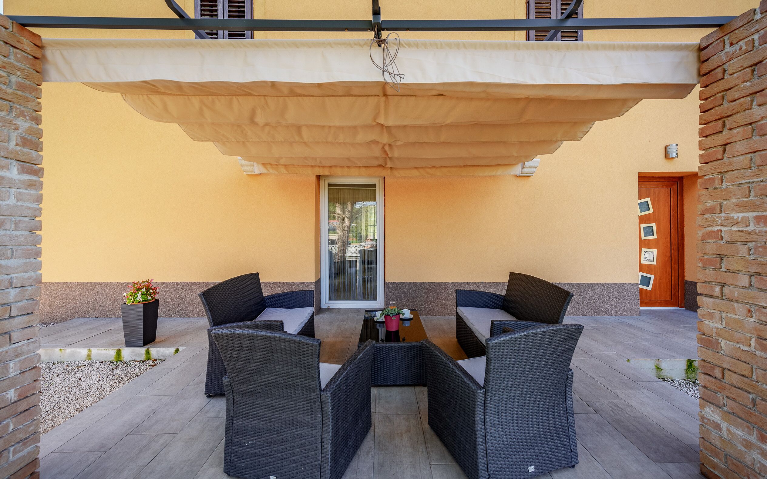A patio with two wicker chairs, a table, and a large umbrella.
